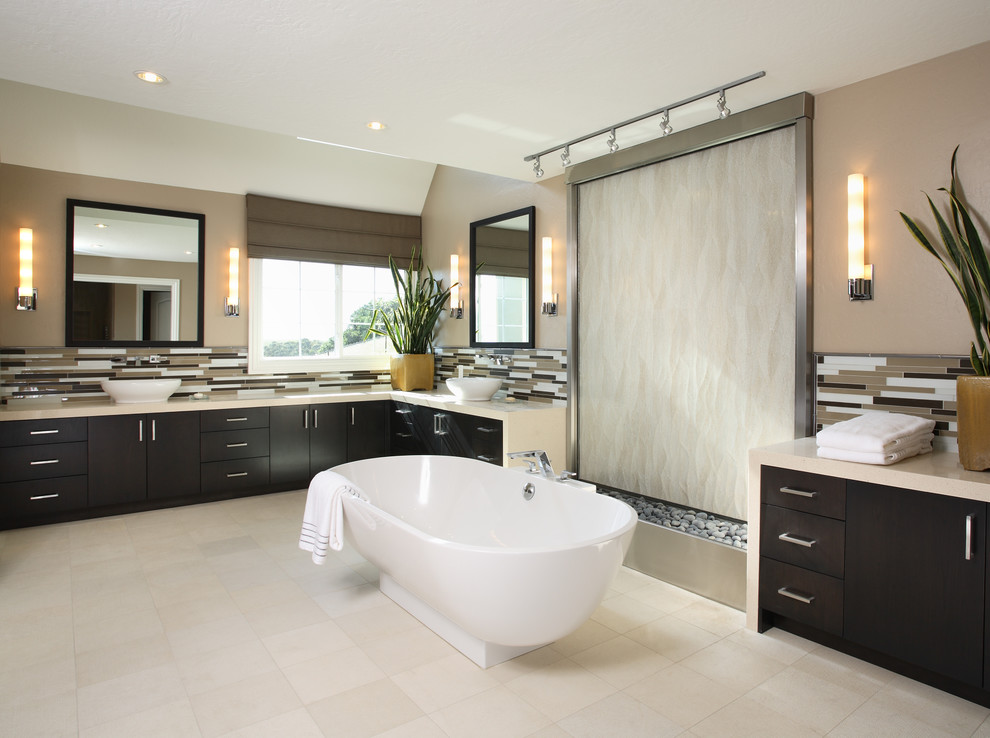 Imagen de cuarto de baño actual con bañera exenta, encimeras beige y piedra