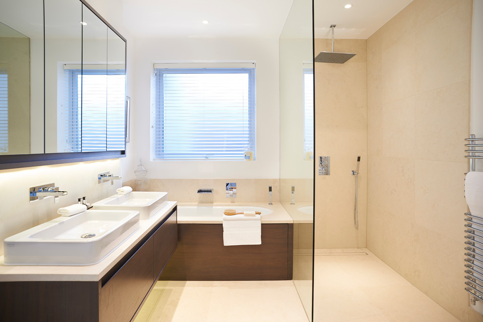Modern inredning av ett litet en-suite badrum, med ett fristående handfat, släta luckor, skåp i mörkt trä, ett undermonterat badkar, en hörndusch och beige kakel