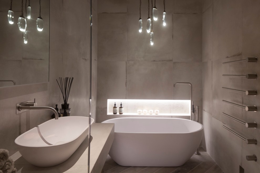 This is an example of a medium sized contemporary ensuite bathroom in Cheshire with a trough sink, freestanding cabinets, distressed cabinets, a freestanding bath, a shower/bath combination, a wall mounted toilet, white tiles, porcelain tiles, white walls and porcelain flooring.