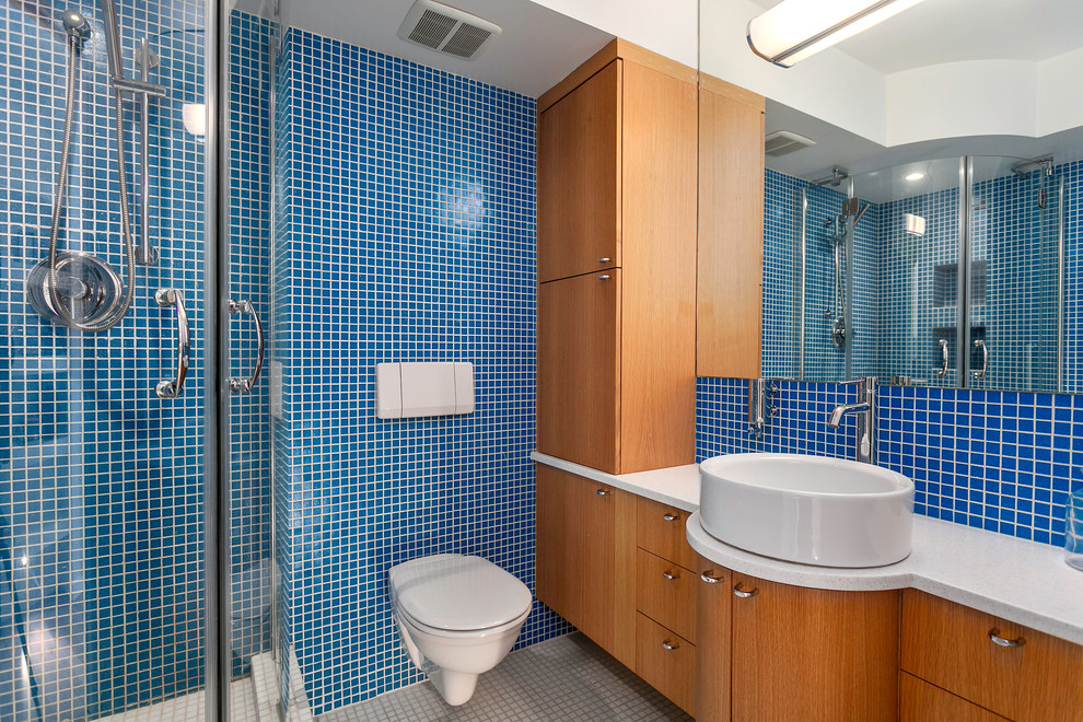Inspiration för ett funkis badrum, med ett fristående handfat, släta luckor, skåp i mellenmörkt trä, en hörndusch, en vägghängd toalettstol, blå kakel, mosaik, blå väggar och mosaikgolv