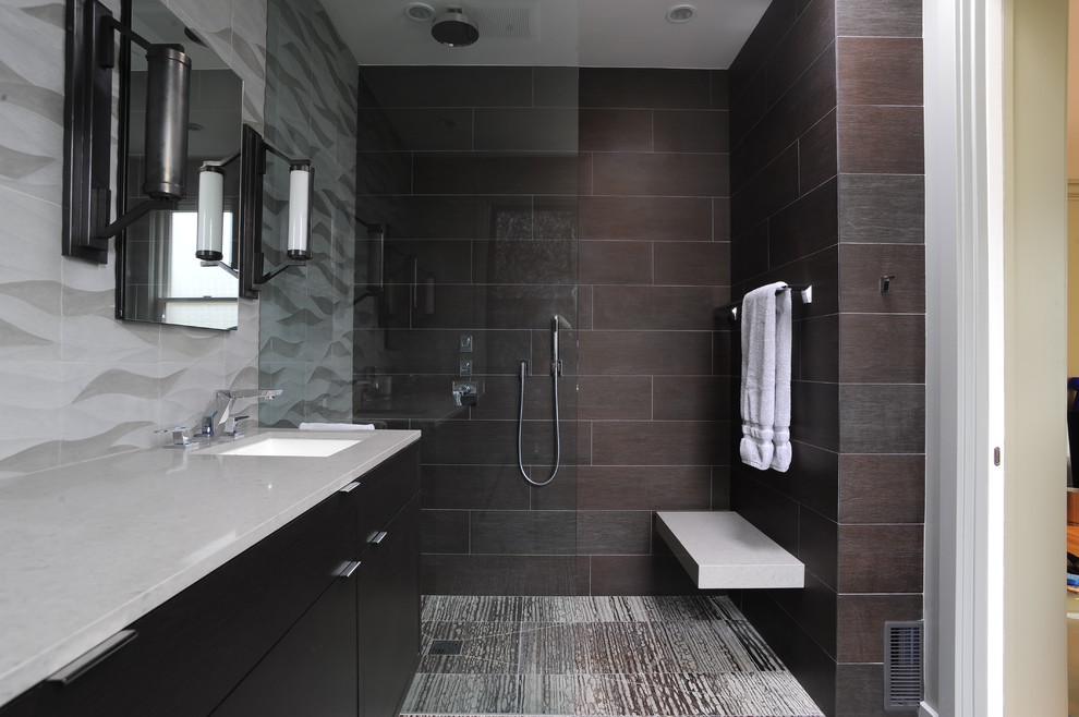 На фото: ванная комната в современном стиле с врезной раковиной, плоскими фасадами, темными деревянными фасадами, душем без бортиков и коричневой плиткой с