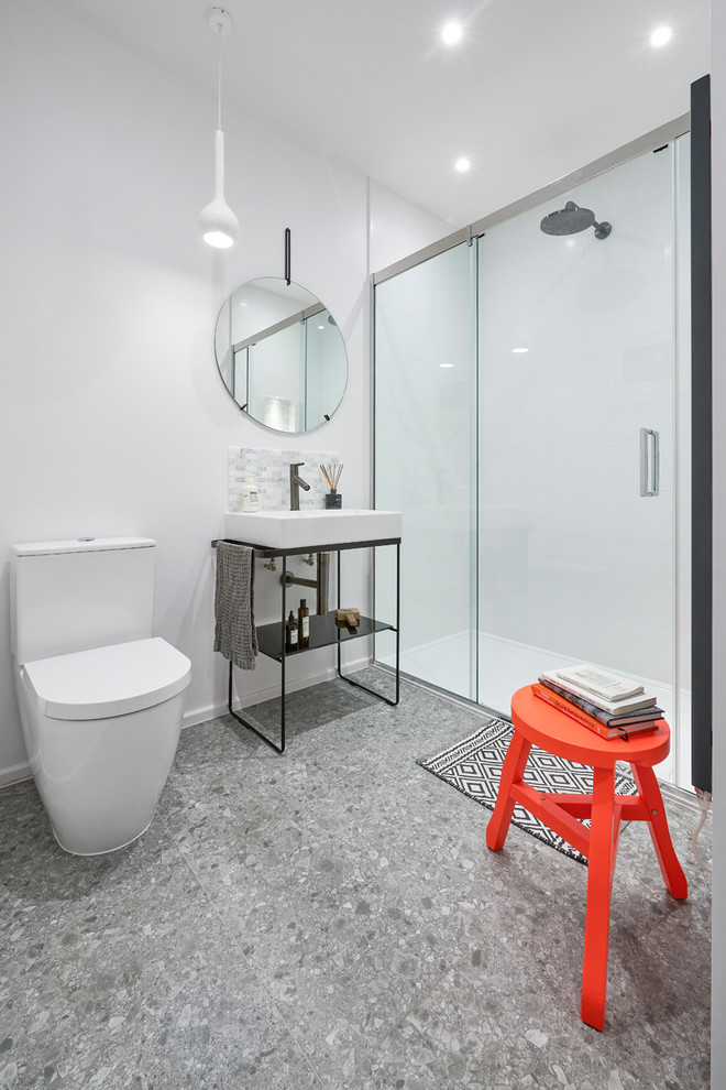Modern inredning av ett mellanstort badrum med dusch, med öppna hyllor, vita väggar, ett konsol handfat, grått golv, dusch med skjutdörr, en dusch i en alkov, en toalettstol med hel cisternkåpa och vit kakel