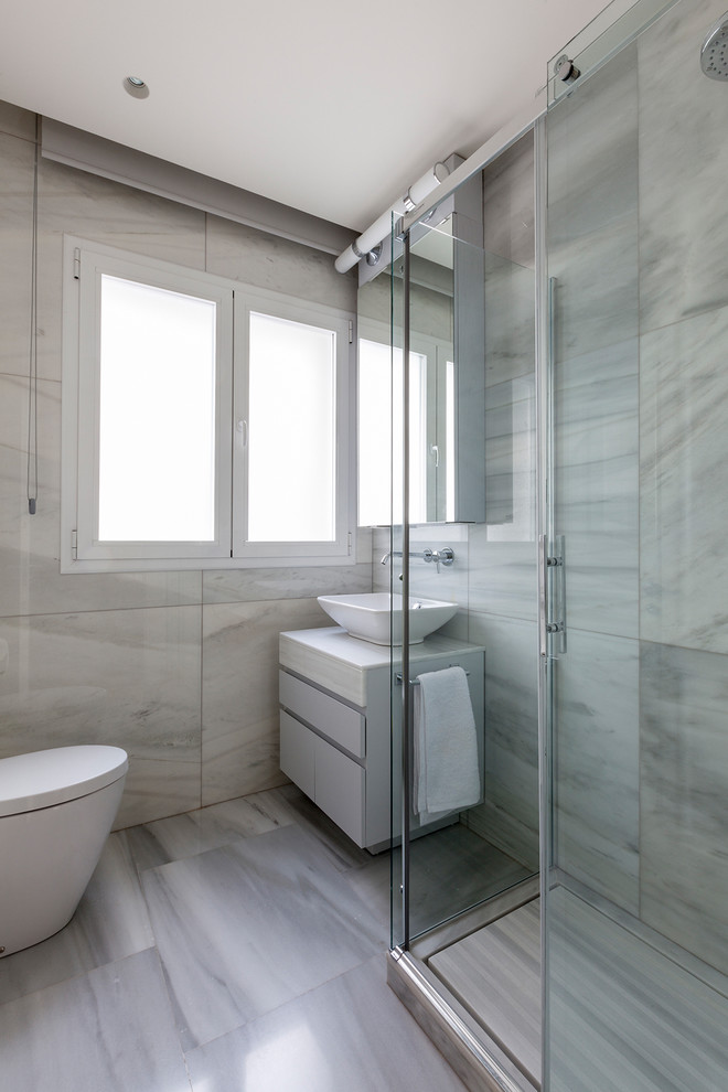 Стильный дизайн: ванная комната в современном стиле с плоскими фасадами, серыми фасадами, угловым душем, инсталляцией, разноцветной плиткой, бежевыми стенами, настольной раковиной и душем с раздвижными дверями - последний тренд