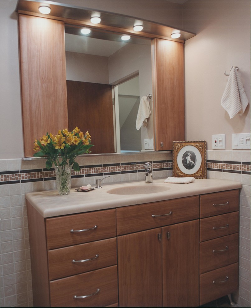 Immagine di una stanza da bagno design con lavabo integrato, ante lisce, top in superficie solida, piastrelle beige, piastrelle a mosaico, pareti rosa, pavimento in gres porcellanato e WC a due pezzi