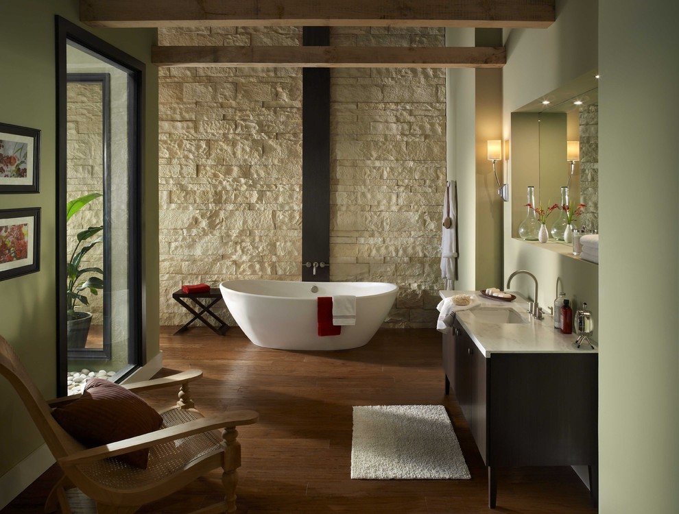 Imagen de cuarto de baño actual con bañera exenta, paredes verdes y piedra