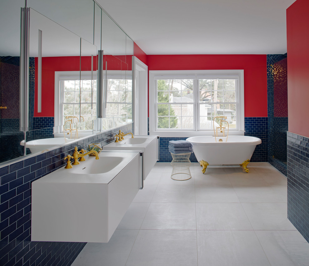Exemple d'une salle de bain principale tendance avec un placard à porte plane, des portes de placard blanches, une baignoire sur pieds, un carrelage bleu, un carrelage métro, un mur rouge, un lavabo intégré et un sol gris.