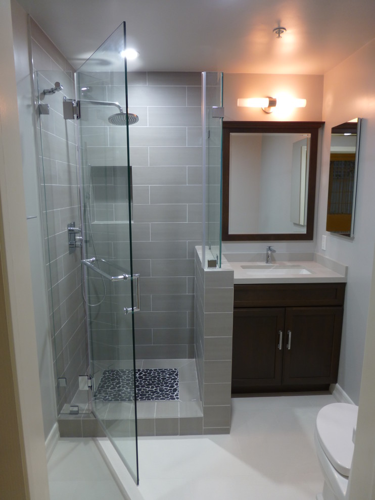Inspiration for a small contemporary 3/4 gray tile and porcelain tile porcelain tile corner shower remodel in Los Angeles with an undermount sink, recessed-panel cabinets, dark wood cabinets, quartz countertops, gray walls and a one-piece toilet