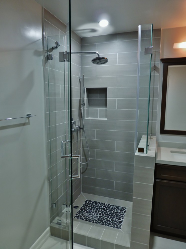 Inredning av ett modernt litet badrum med dusch, med ett undermonterad handfat, luckor med infälld panel, skåp i mörkt trä, bänkskiva i kvarts, en hörndusch, en toalettstol med hel cisternkåpa, grå kakel, porslinskakel, grå väggar och klinkergolv i porslin