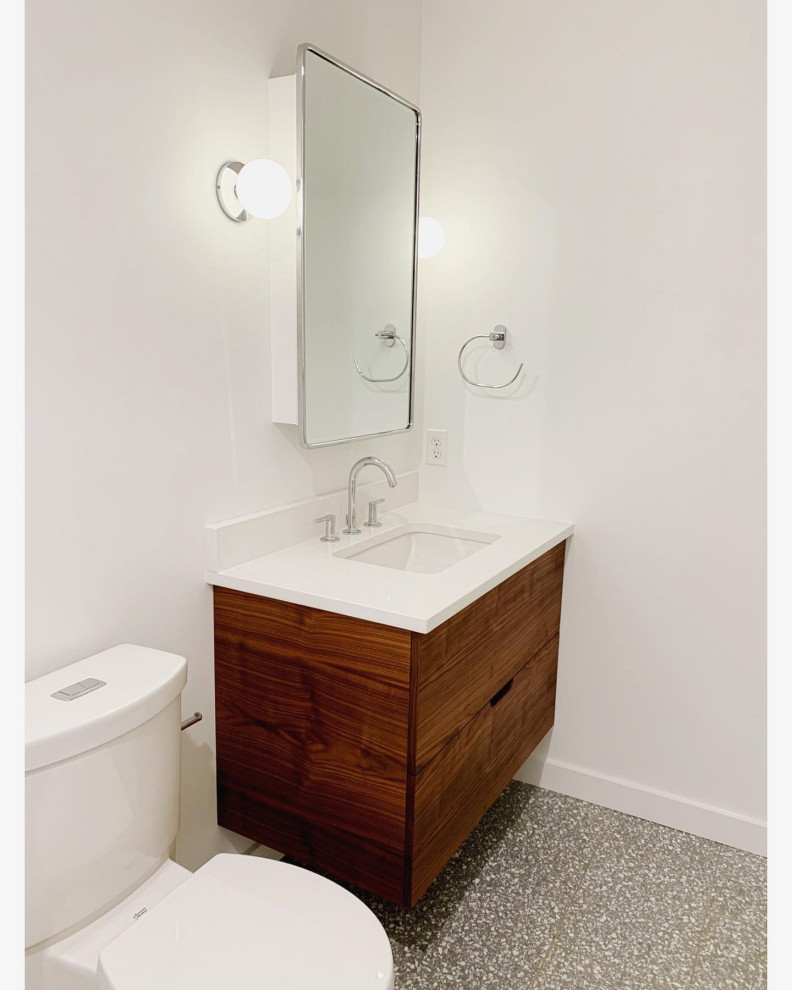 Small contemporary bathroom in Philadelphia with flat-panel cabinets, dark wood cabinets, an alcove bath, an alcove shower, a two-piece toilet, white tiles, ceramic tiles, white walls, terrazzo flooring, a built-in sink, engineered stone worktops, grey floors, a hinged door and white worktops.