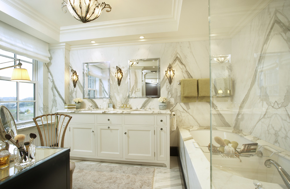 Modelo de cuarto de baño contemporáneo con lavabo bajoencimera, armarios con paneles empotrados, puertas de armario blancas, bañera encastrada sin remate, baldosas y/o azulejos blancos y baldosas y/o azulejos de mármol