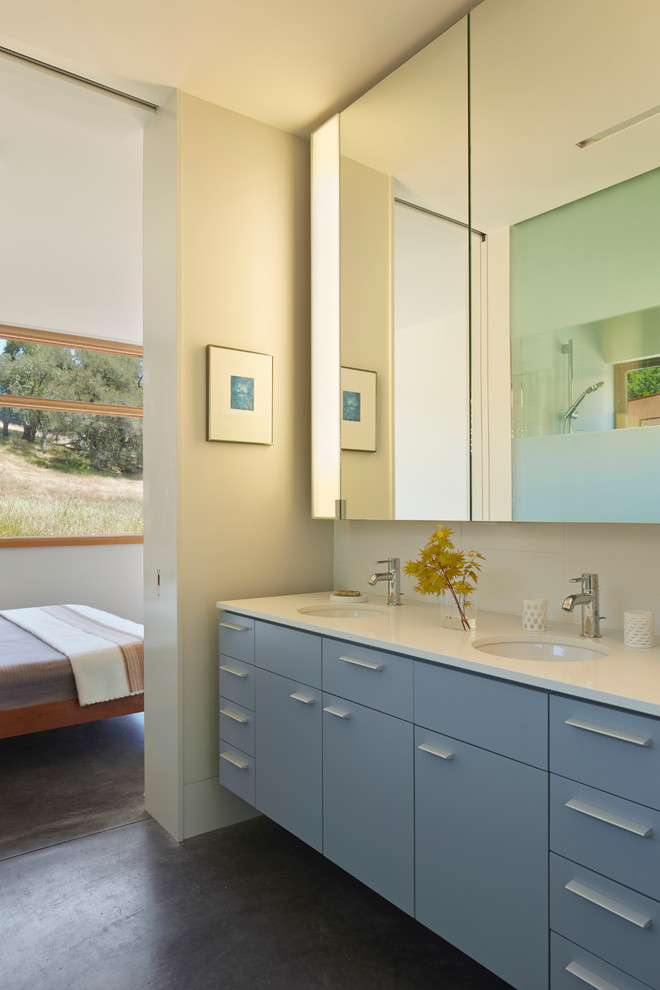 Exemple d'une salle de bain tendance avec un lavabo encastré, un placard à porte plane et des portes de placard bleues.