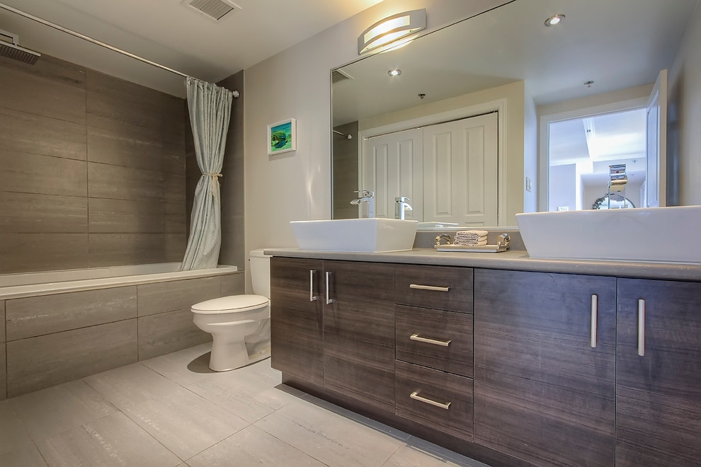 Example of a trendy gray tile and ceramic tile bathroom design in Montreal with a drop-in sink, flat-panel cabinets, dark wood cabinets, laminate countertops and a one-piece toilet