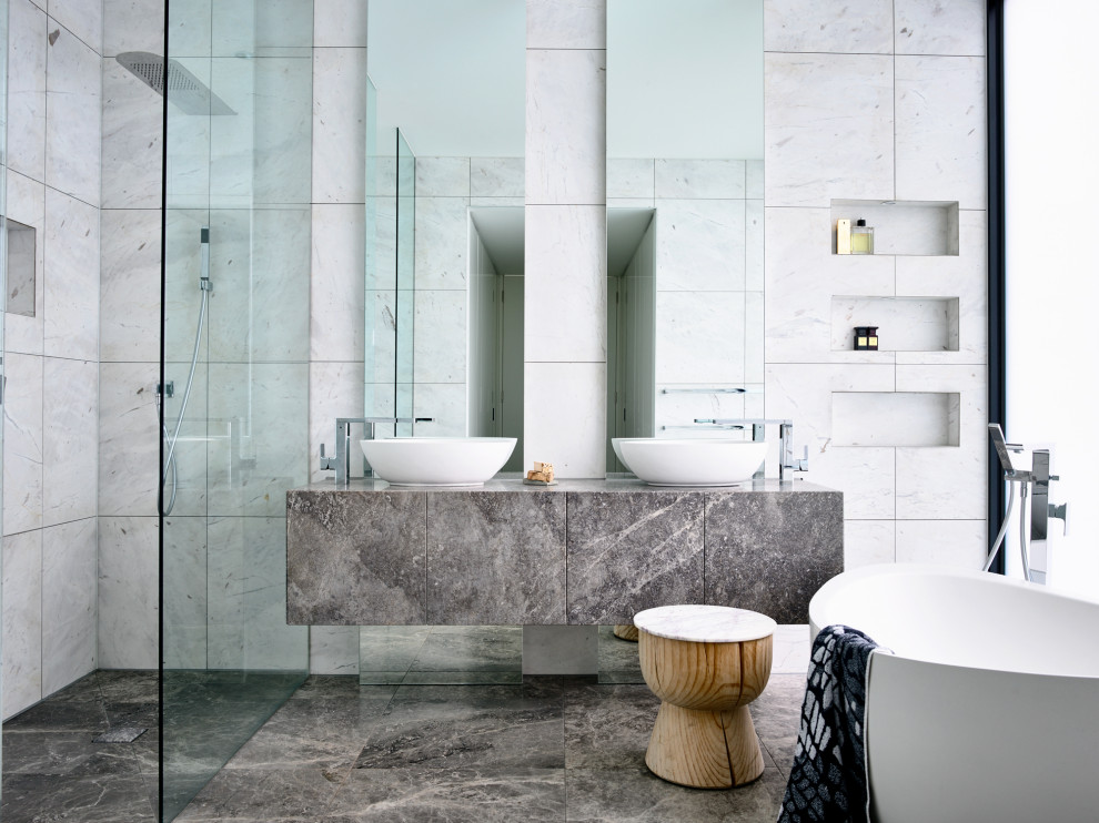 Modelo de cuarto de baño principal contemporáneo grande con armarios con paneles lisos, puertas de armario grises, bañera exenta, ducha esquinera, baldosas y/o azulejos grises, lavabo sobreencimera, suelo gris y encimeras grises