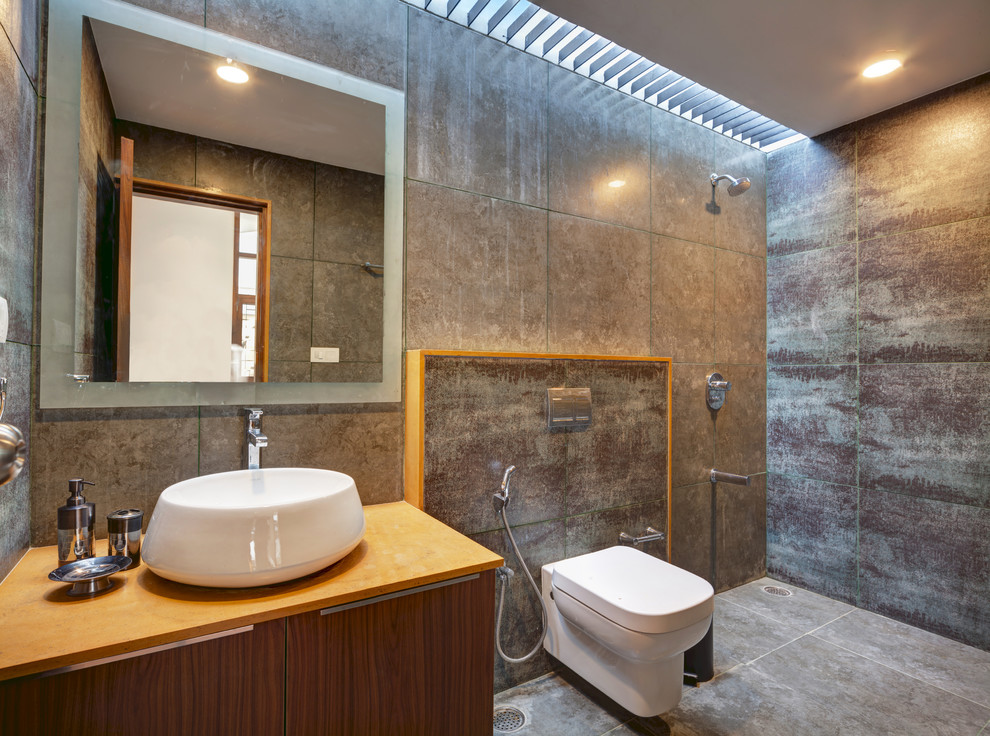 Réalisation d'une salle d'eau design en bois brun avec un placard à porte plane, une douche ouverte, WC suspendus, un carrelage gris, une vasque, un sol gris, aucune cabine et un plan de toilette orange.
