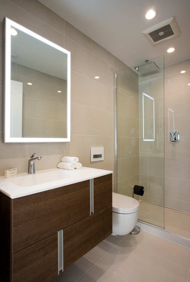 Bild på ett funkis badrum, med ett integrerad handfat, en dusch i en alkov, en vägghängd toalettstol, beige kakel, keramikplattor, släta luckor och skåp i mörkt trä