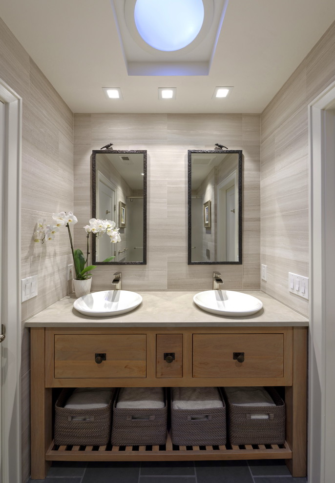 Example of a mid-sized trendy kids' gray tile and marble tile slate floor and black floor bathroom design in DC Metro with furniture-like cabinets, medium tone wood cabinets, a wall-mount toilet, gray walls, a vessel sink, limestone countertops and gray countertops