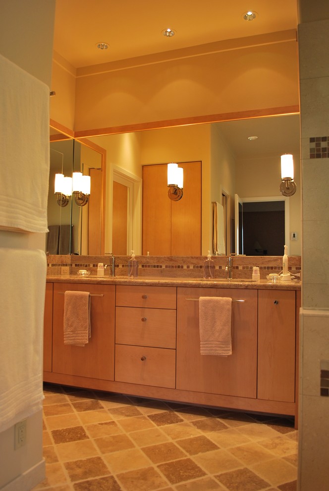 Immagine di una stanza da bagno minimal di medie dimensioni con ante lisce, ante in legno chiaro, vasca ad alcova, doccia ad angolo, piastrelle beige, piastrelle in pietra, pavimento in travertino, lavabo sottopiano e top in granito