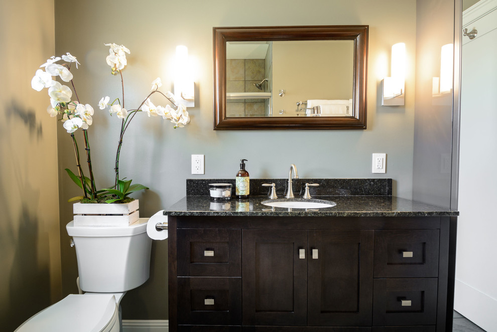 Exemple d'une salle de bain tendance de taille moyenne avec un placard à porte shaker, des portes de placard marrons, une baignoire en alcôve, un combiné douche/baignoire, WC séparés, un carrelage beige, des carreaux de porcelaine, un mur gris, un sol en carrelage de porcelaine, un lavabo encastré et un plan de toilette en granite.
