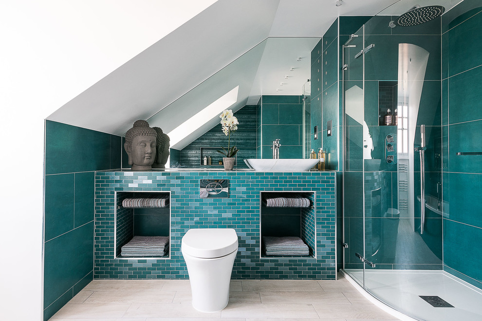 Modelo de cuarto de baño actual con ducha esquinera, sanitario de pared, baldosas y/o azulejos azules, paredes blancas y lavabo sobreencimera
