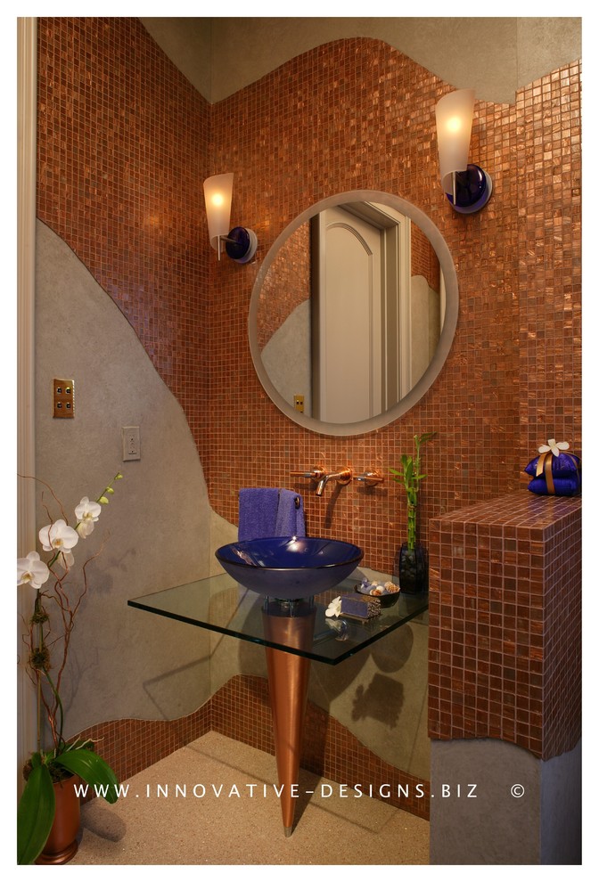 Modern inredning av ett litet badrum med dusch, med ett fristående handfat, luckor med glaspanel, bänkskiva i glas, en toalettstol med hel cisternkåpa, brun kakel, glaskakel, bruna väggar och mosaikgolv