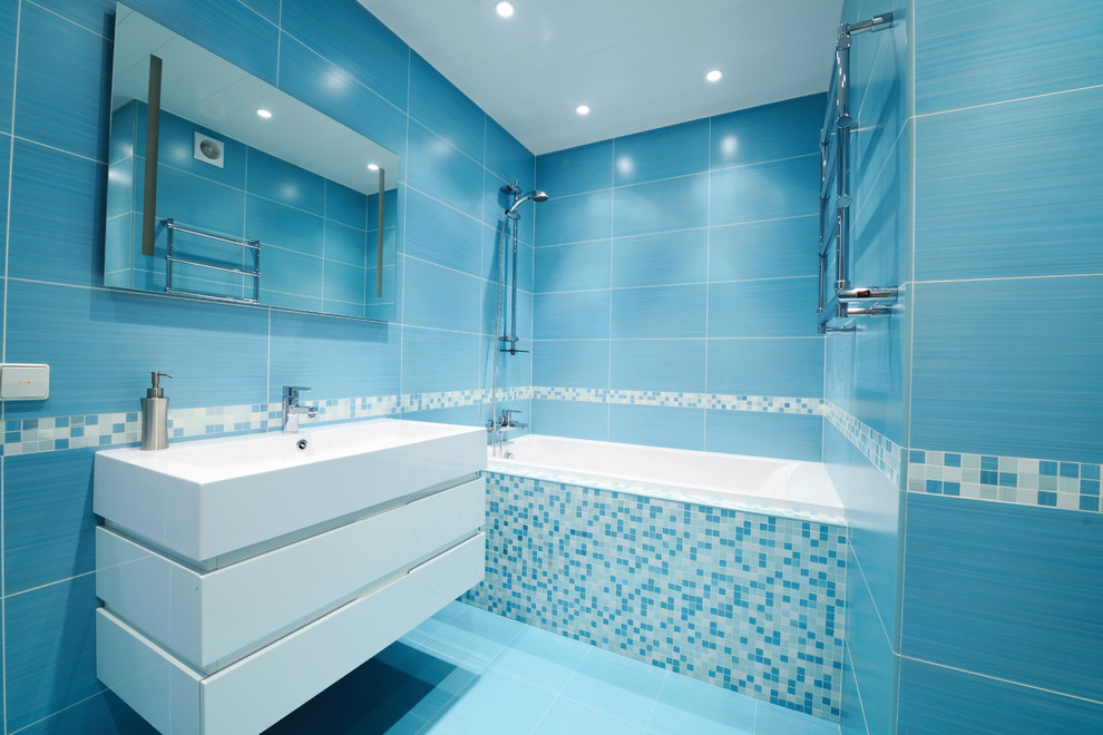 Свежая идея для дизайна: ванная комната среднего размера в современном стиле с плоскими фасадами, белыми фасадами, ванной в нише, душем над ванной, унитазом-моноблоком, синей плиткой, керамогранитной плиткой, синими стенами, полом из керамогранита, душевой кабиной, монолитной раковиной, столешницей из искусственного камня и открытым душем - отличное фото интерьера