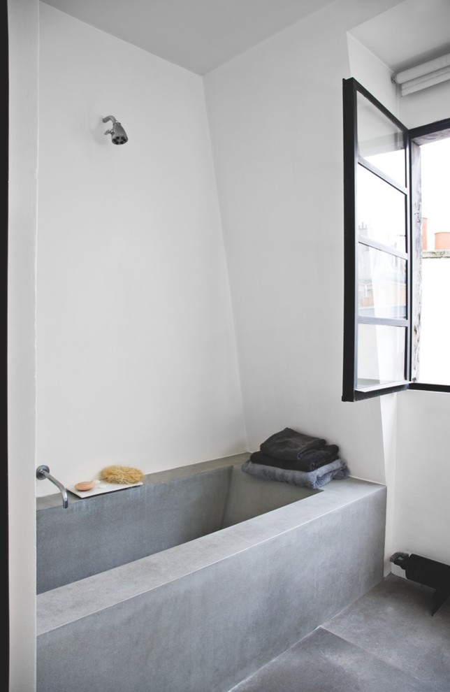 Idéer för små funkis en-suite badrum, med ett badkar i en alkov, en dusch/badkar-kombination, vita väggar och betonggolv