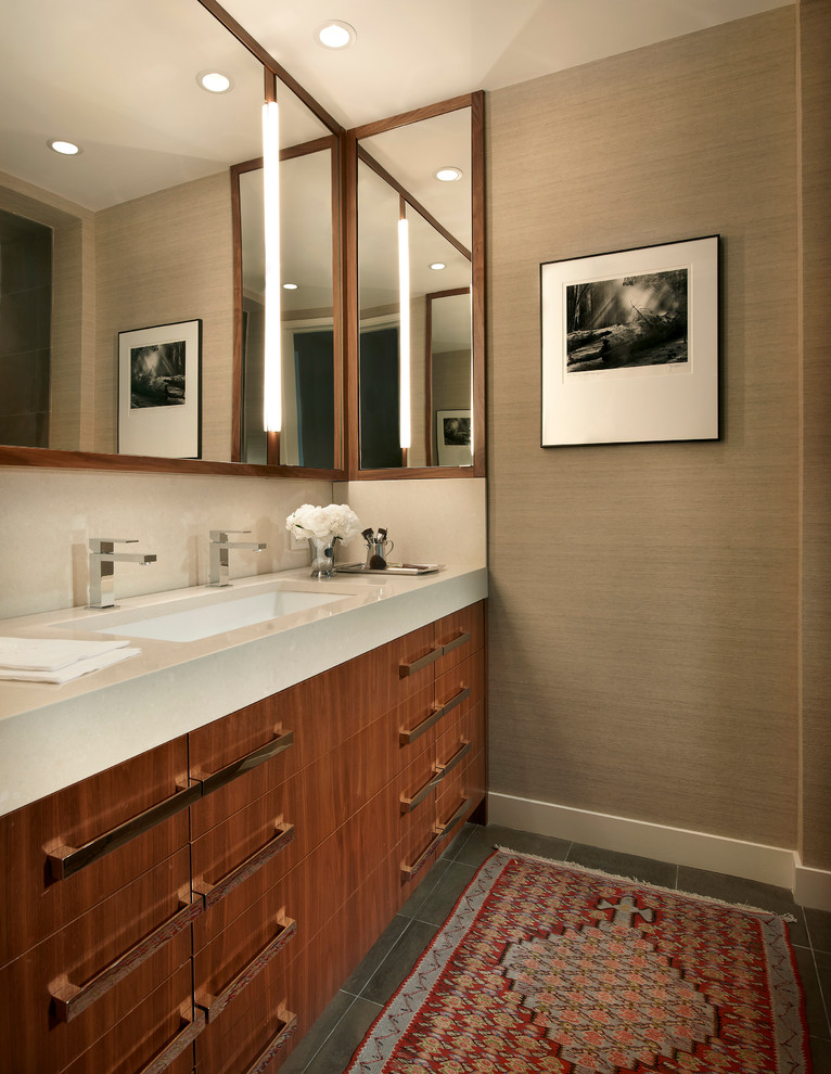 Modern inredning av ett badrum, med ett undermonterad handfat, släta luckor, skåp i mörkt trä och beige väggar