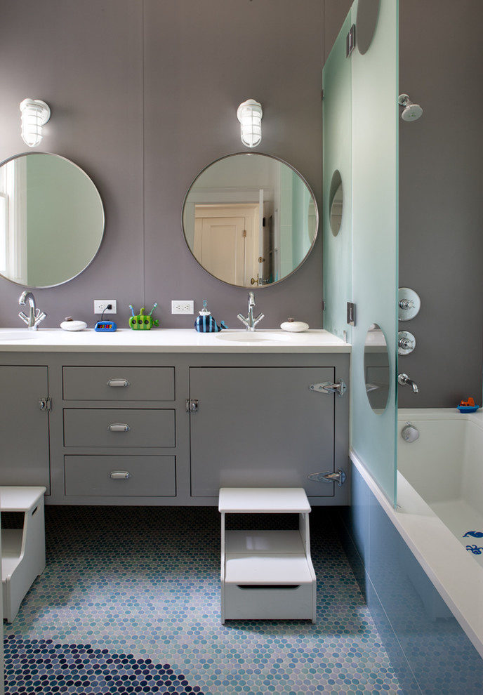 Exemple d'une salle de bain tendance de taille moyenne pour enfant avec des portes de placard grises, un placard à porte plane, un mur gris, un sol en carrelage de terre cuite, une baignoire encastrée, un combiné douche/baignoire, un lavabo encastré, un plan de toilette en stéatite, un sol bleu, une cabine de douche à porte battante, un plan de toilette blanc, meuble double vasque et meuble-lavabo suspendu.