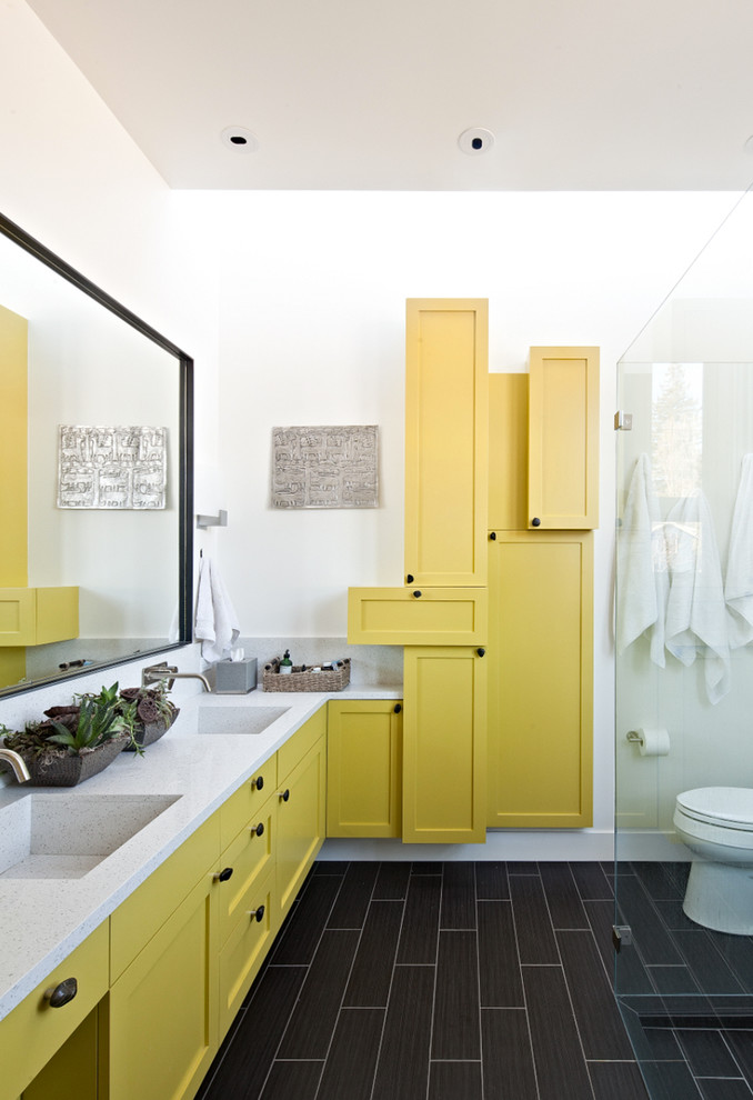 На фото: ванная комната в современном стиле с монолитной раковиной, фасадами в стиле шейкер, желтыми фасадами, душем без бортиков и коричневой плиткой
