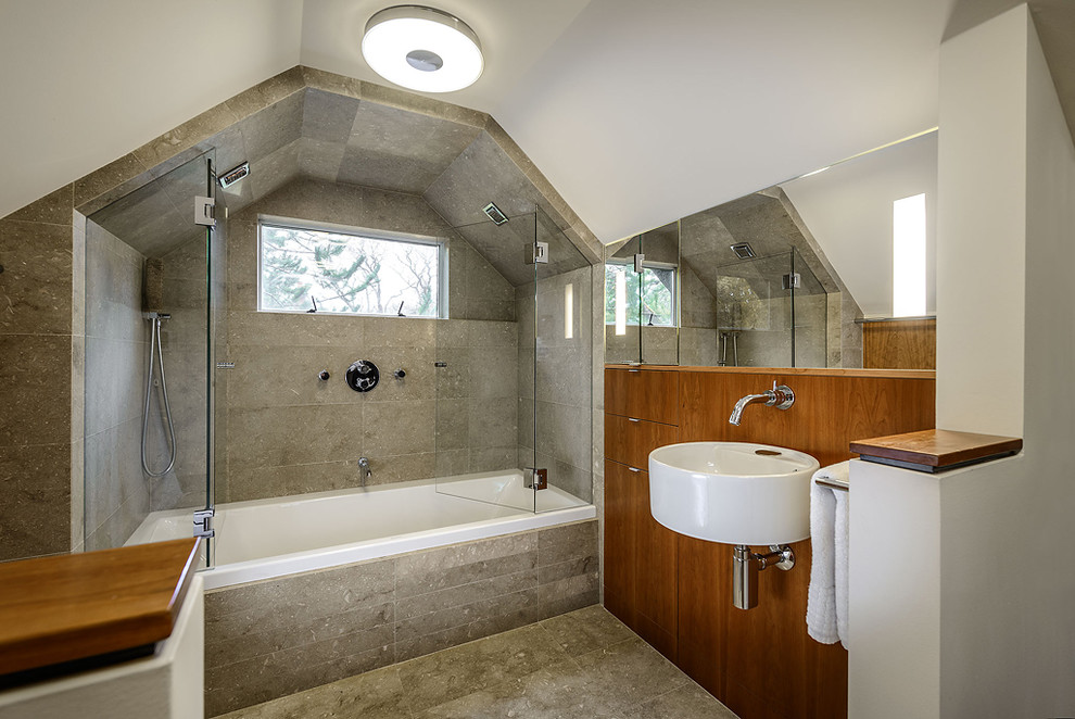 Ejemplo de cuarto de baño contemporáneo con lavabo suspendido, armarios con paneles lisos, puertas de armario de madera oscura, bañera empotrada y baldosas y/o azulejos grises