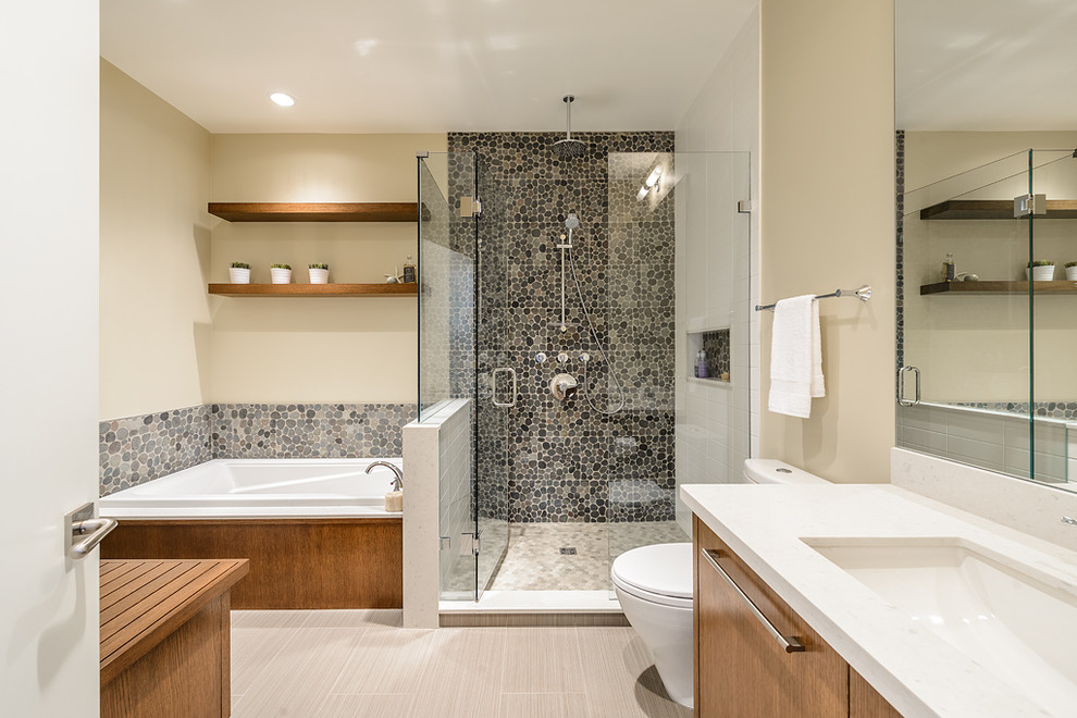 Ispirazione per una stanza da bagno minimal con lavabo sottopiano, ante lisce, ante in legno scuro, vasca da incasso, doccia alcova, piastrelle grigie e piastrelle in pietra