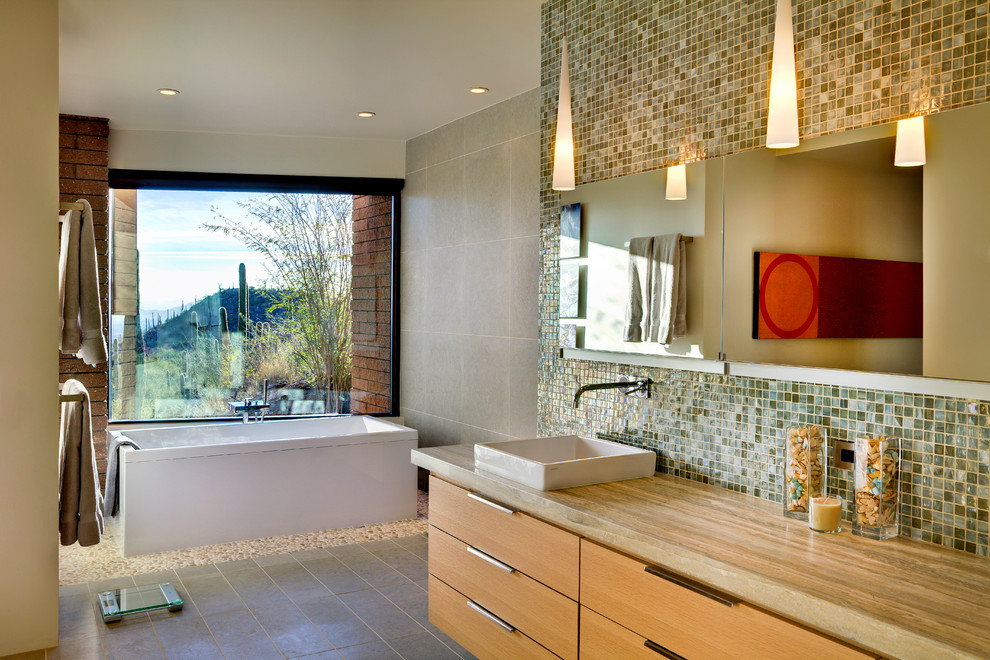Exempel på ett stort modernt en-suite badrum, med ett fristående handfat, släta luckor, skåp i mellenmörkt trä, ett fristående badkar, grön kakel, mosaik och klinkergolv i småsten
