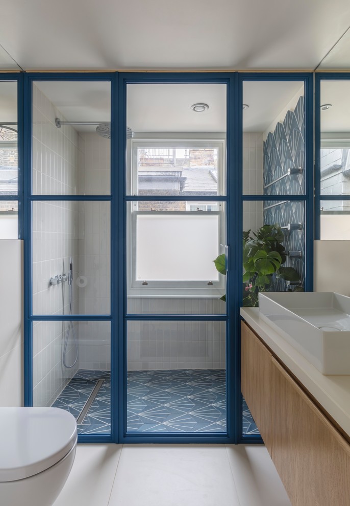 Idee per una stanza da bagno minimal con ante lisce, ante in legno chiaro, zona vasca/doccia separata, piastrelle blu, pareti beige, lavabo a bacinella, pavimento blu, porta doccia a battente e top beige