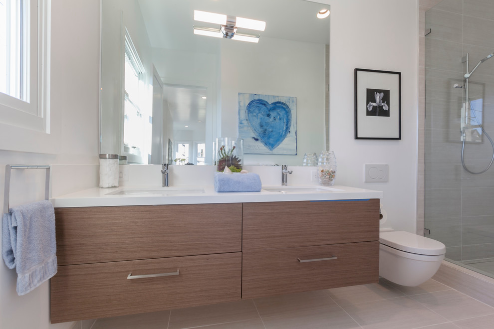 Inredning av ett modernt mellanstort en-suite badrum, med ett nedsänkt handfat, släta luckor, skåp i mellenmörkt trä, bänkskiva i kvarts, en dusch i en alkov, en vägghängd toalettstol, grå kakel, vita väggar och klinkergolv i porslin