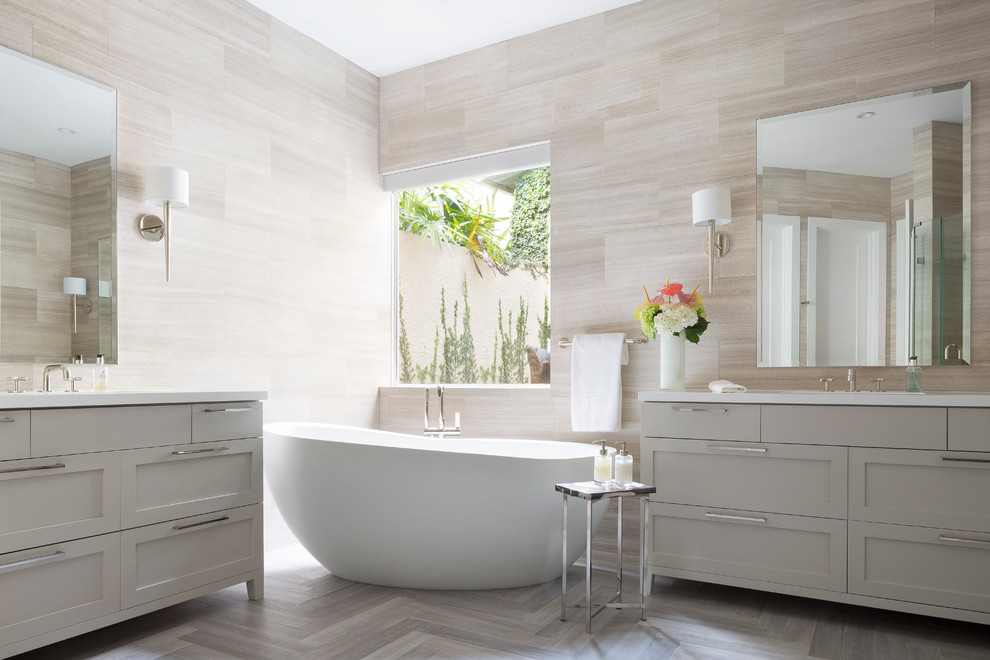 Foto di una stanza da bagno padronale contemporanea di medie dimensioni con lavabo sottopiano, ante in stile shaker, ante grigie, top in superficie solida, vasca freestanding, piastrelle beige, lastra di pietra e pavimento in marmo