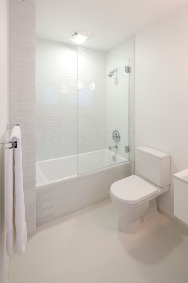 Пример оригинального дизайна: главная ванная комната среднего размера в современном стиле с душем над ванной, раздельным унитазом, белой плиткой, белыми стенами, полом из керамической плитки, плоскими фасадами, белыми фасадами, ванной в нише, плиткой кабанчик, настольной раковиной и столешницей из искусственного кварца