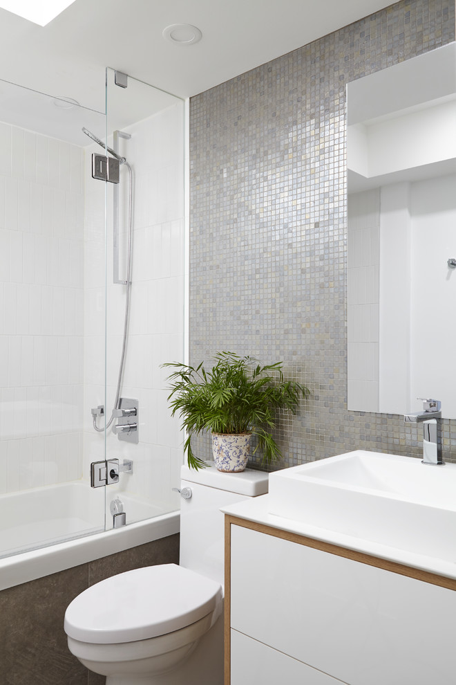 Свежая идея для дизайна: ванная комната в современном стиле с белыми фасадами, душем в нише, унитазом-моноблоком, серой плиткой, плиткой мозаикой, настольной раковиной, душем с распашными дверями, белой столешницей и плоскими фасадами - отличное фото интерьера