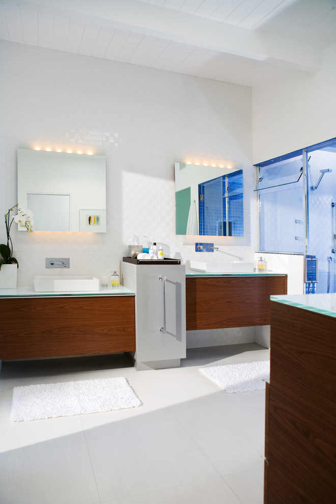 На фото: главная ванная комната в современном стиле с настольной раковиной, плоскими фасадами, темными деревянными фасадами, открытым душем, унитазом-моноблоком, синей плиткой, белой плиткой, керамической плиткой, белыми стенами, полом из керамогранита, стеклянной столешницей и белым полом