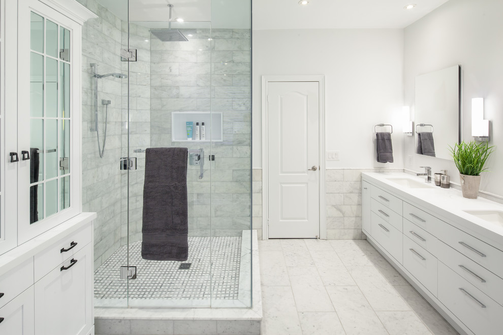 Cette image montre une salle de bain principale design de taille moyenne avec un lavabo encastré, un placard à porte plane, des portes de placard blanches, une douche d'angle, un carrelage blanc, un carrelage de pierre, un mur blanc, une baignoire indépendante, un sol en marbre et un plan de toilette en quartz modifié.