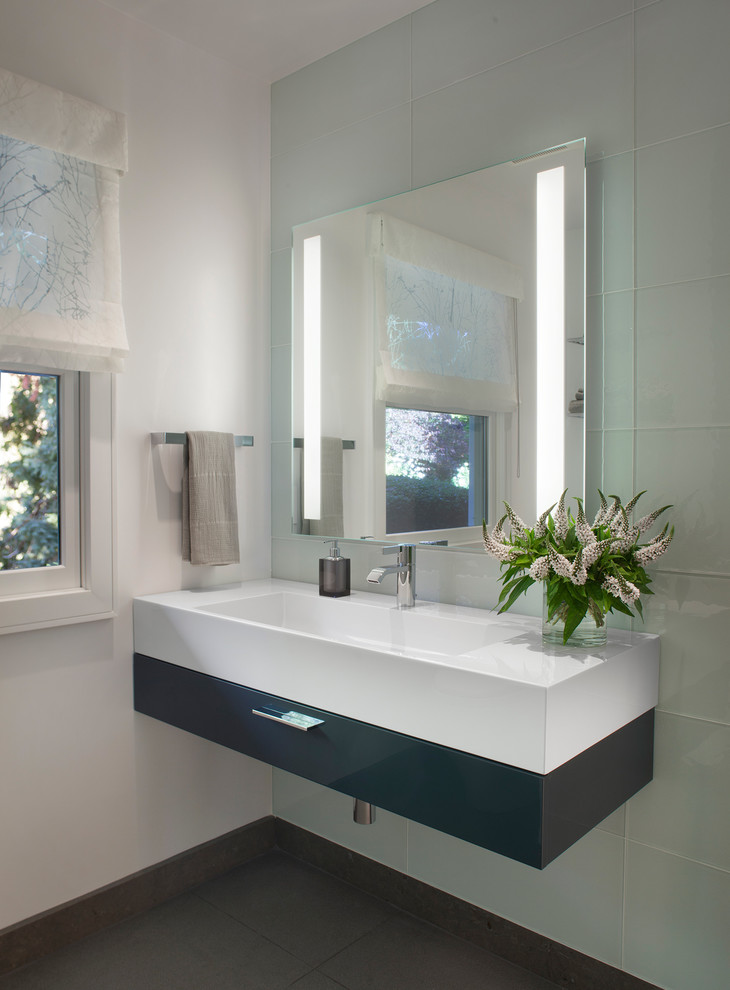 Ejemplo de cuarto de baño actual con lavabo integrado, armarios con paneles lisos, puertas de armario negras, paredes blancas y espejo con luz