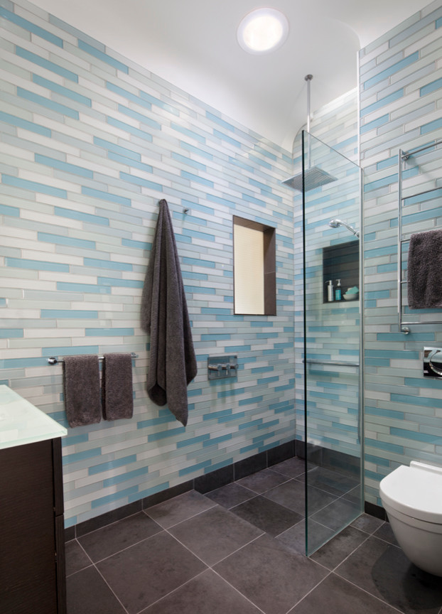 На фото: главная ванная комната среднего размера в современном стиле с плоскими фасадами, темными деревянными фасадами, душем без бортиков, биде, синей плиткой, стеклянной плиткой, синими стенами, полом из керамогранита и стеклянной столешницей с