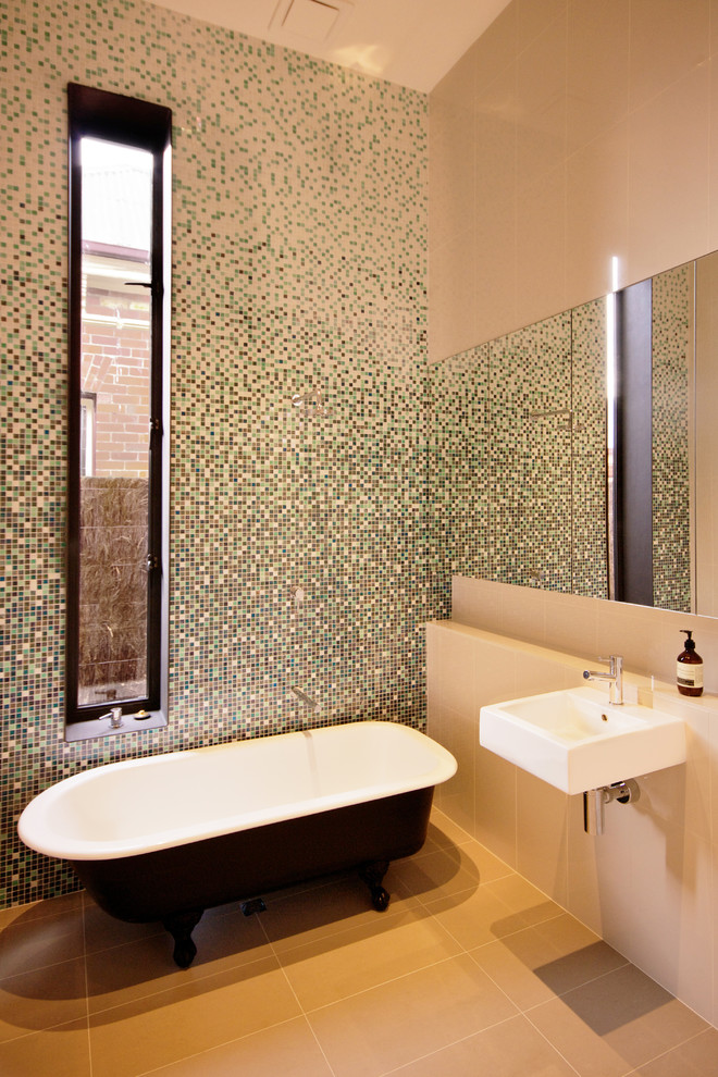 Immagine di una stanza da bagno minimal con vasca con piedi a zampa di leone, piastrelle a mosaico e lavabo sospeso