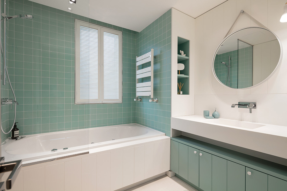 На фото: ванная комната в современном стиле с плоскими фасадами, зелеными фасадами, накладной ванной, душем над ванной, зеленой плиткой, белой плиткой, плиткой мозаикой, белыми стенами, полом из мозаичной плитки, монолитной раковиной, белым полом, открытым душем и белой столешницей