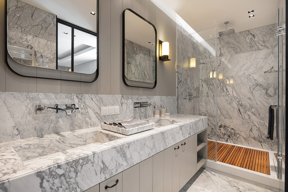 Photo of a contemporary ensuite bathroom in New York with flat-panel cabinets, grey cabinets, an alcove shower, grey tiles, grey walls, an integrated sink, grey floors, a hinged door, grey worktops, marble tiles, marble flooring and marble worktops.