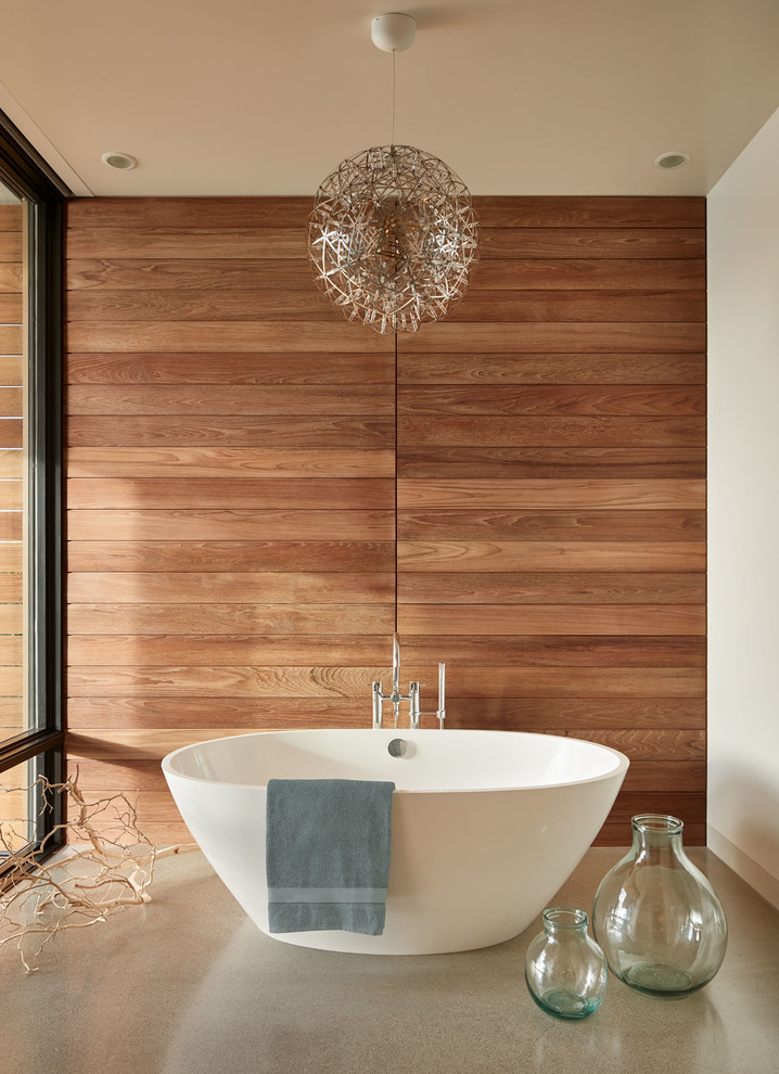 Diseño de cuarto de baño contemporáneo con bañera exenta, paredes blancas, suelo de cemento y suelo gris