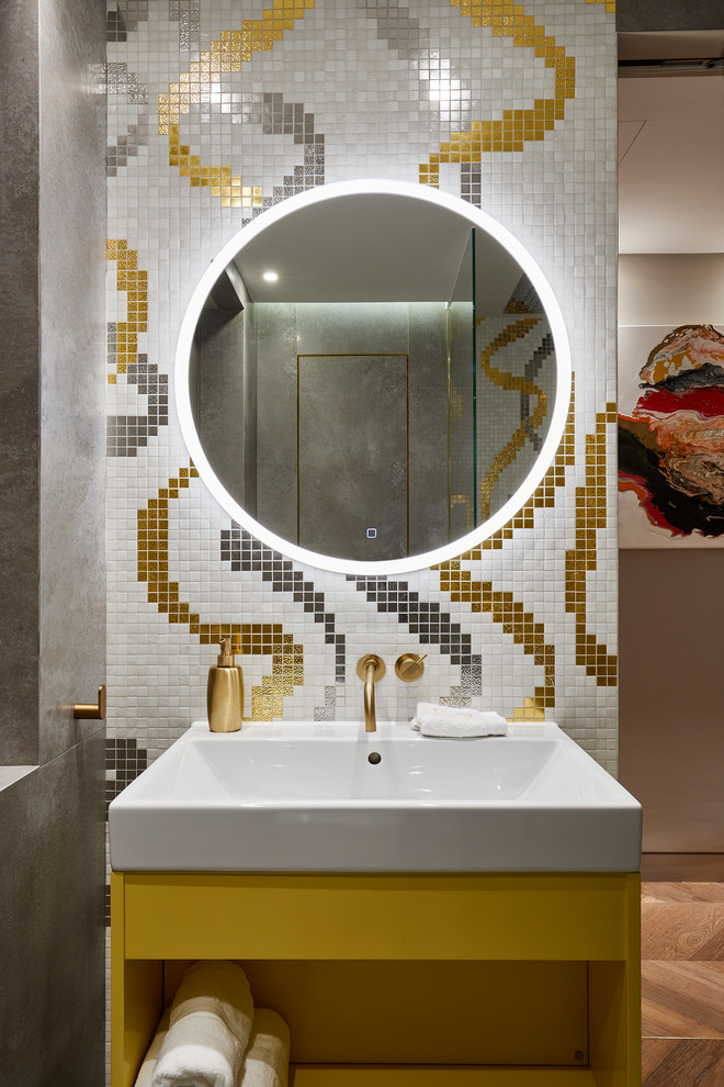 Идея дизайна: ванная комната в современном стиле с открытыми фасадами, желтыми фасадами, разноцветной плиткой, плиткой мозаикой, паркетным полом среднего тона, накладной раковиной, коричневым полом и зеркалом с подсветкой