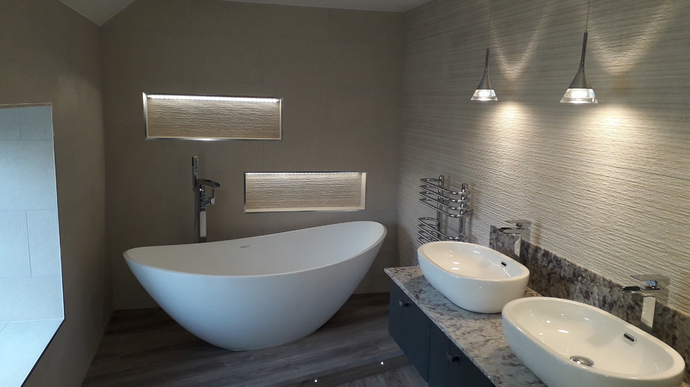 This is an example of a large contemporary family bathroom in West Midlands with a freestanding bath, a wall mounted toilet, white tiles, ceramic tiles, laminate floors, quartz worktops, grey floors and multi-coloured worktops.