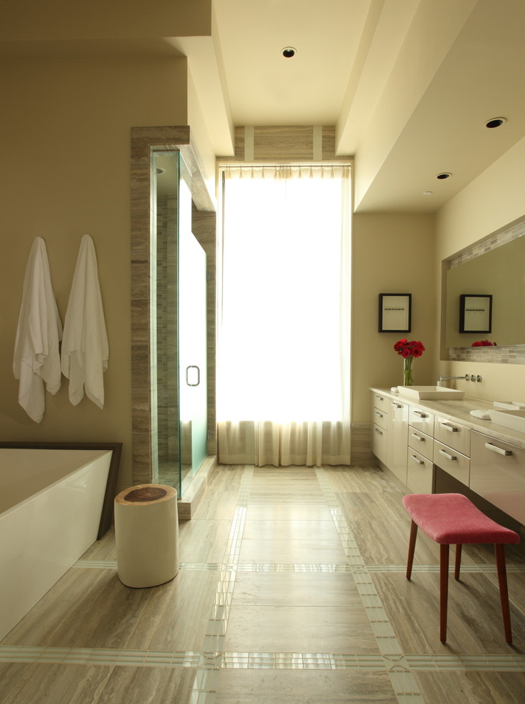 Inredning av ett modernt badrum, med ett fristående badkar, ett fristående handfat och beiget golv