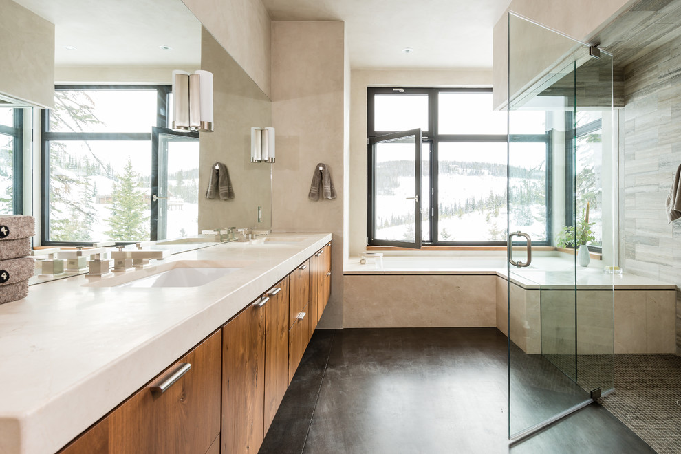 Foto di una stanza da bagno minimal con lavabo sottopiano, ante lisce, ante in legno scuro, piastrelle beige, pavimento nero e top beige