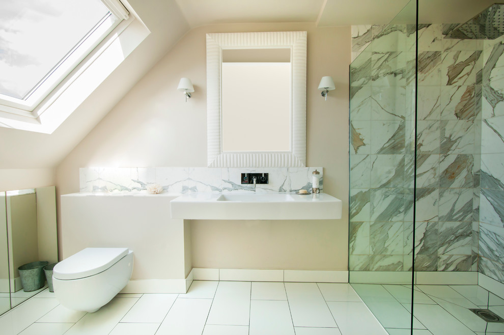 Modern inredning av ett badrum med dusch, med ett integrerad handfat, en kantlös dusch, en vägghängd toalettstol, flerfärgad kakel och beige väggar